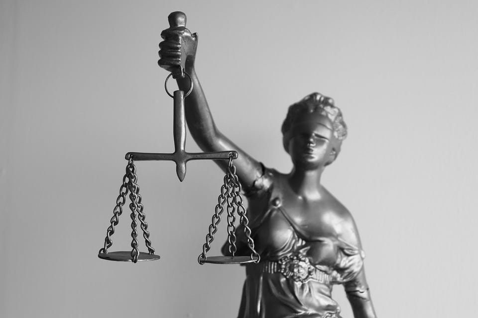 Estátua da deusa Têmis (Justiça), com os olhos vendados, segurando a balança da justiça e uma espada, simbolizando o direito e a imparcialidade. A imagem ilustra um informativo jurídico com decisões de tribunais superiores, como o STJ e o STF.